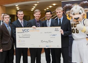 FreeMobility, a team of undergraduate mechanical engineering students, won first place in its division in the 2013 Venture Creation Competition on Apr. 26 at VCU. Pictured from left to right: team members Matthew Schell, Justin Dickerson and John Swanson; VCU President Michael Rao; team member Jonathan Marsh; and Rodney the Ram.