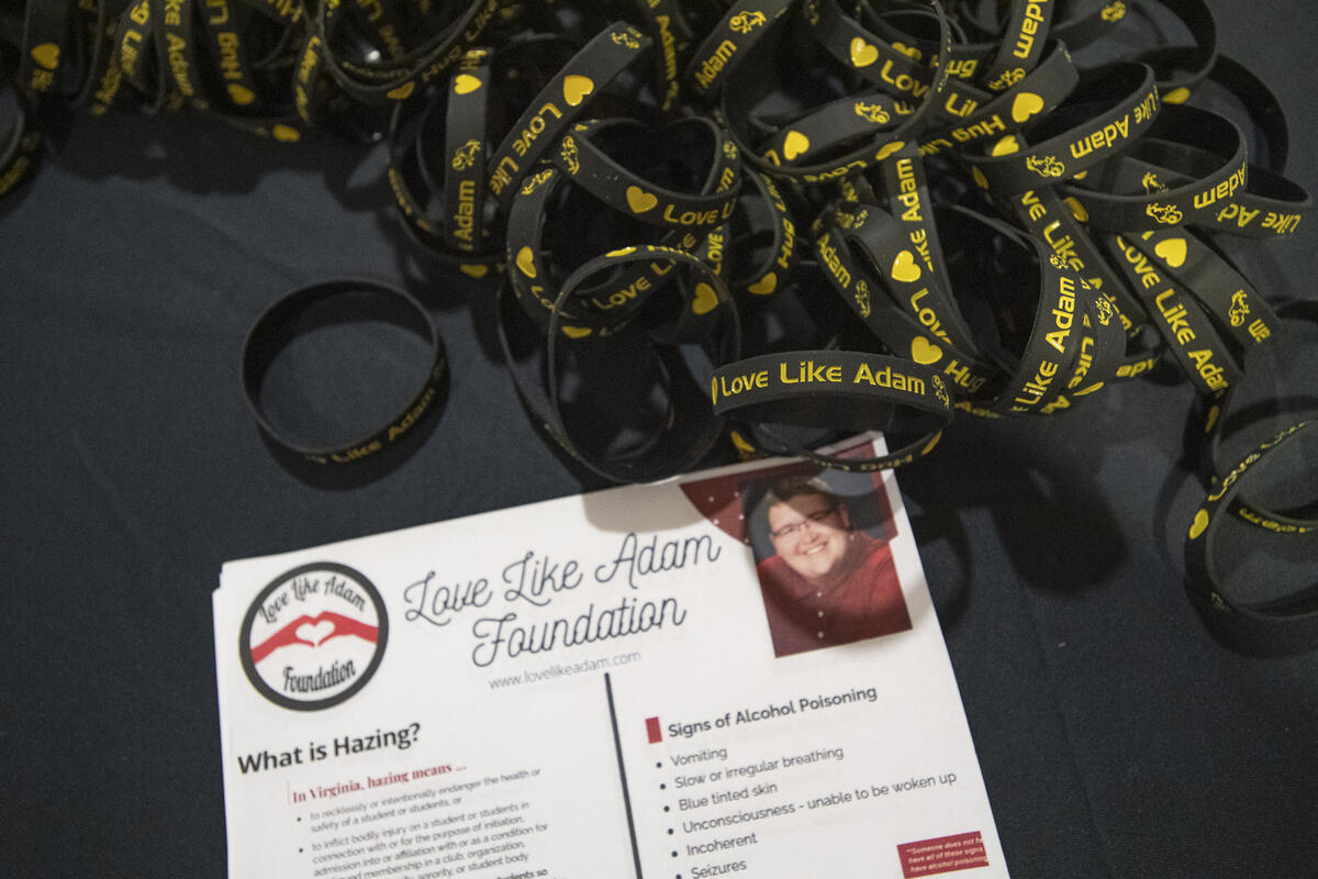 A photo of a card that says \"Love Like Adam Foundation\" next to a pile of black plastic bracelets that say \"Love Like Adam\" in yellow text. 
