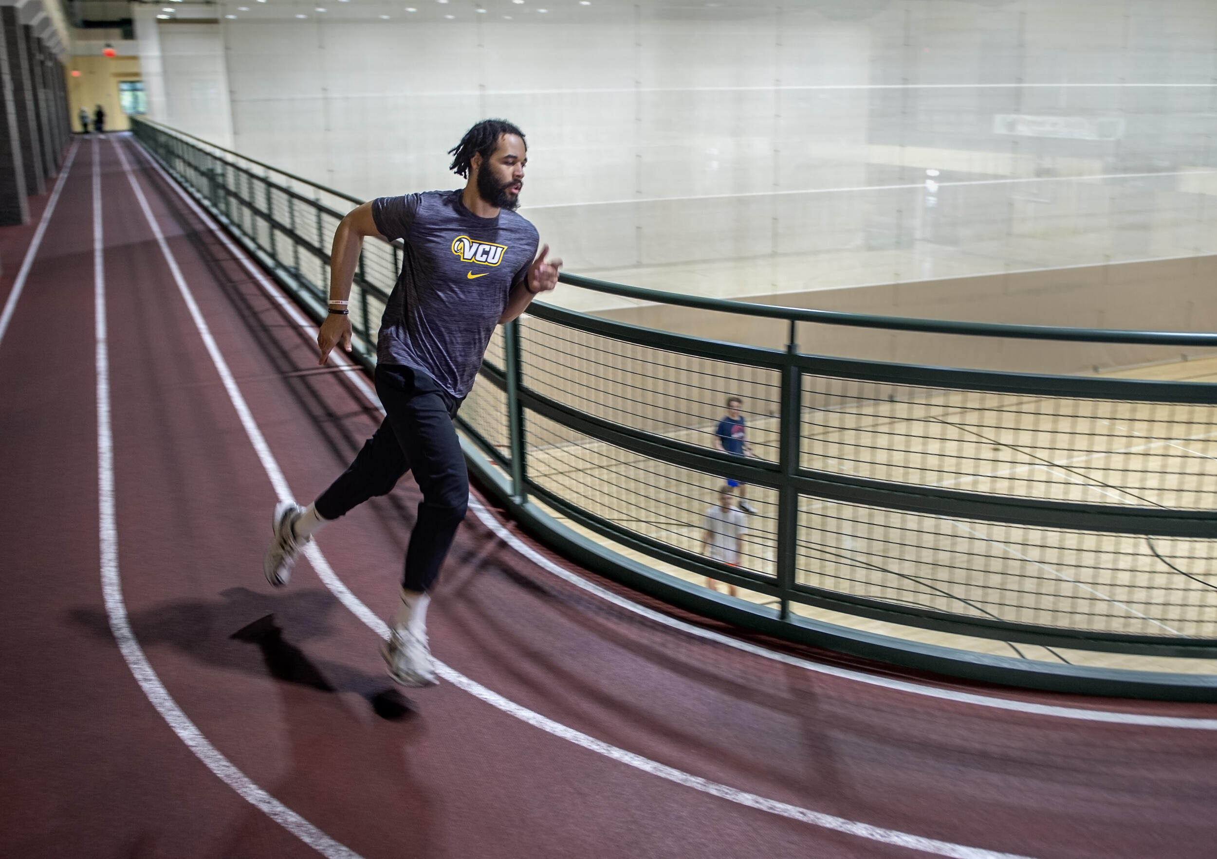 A photo of a man running on an indoor a track. 