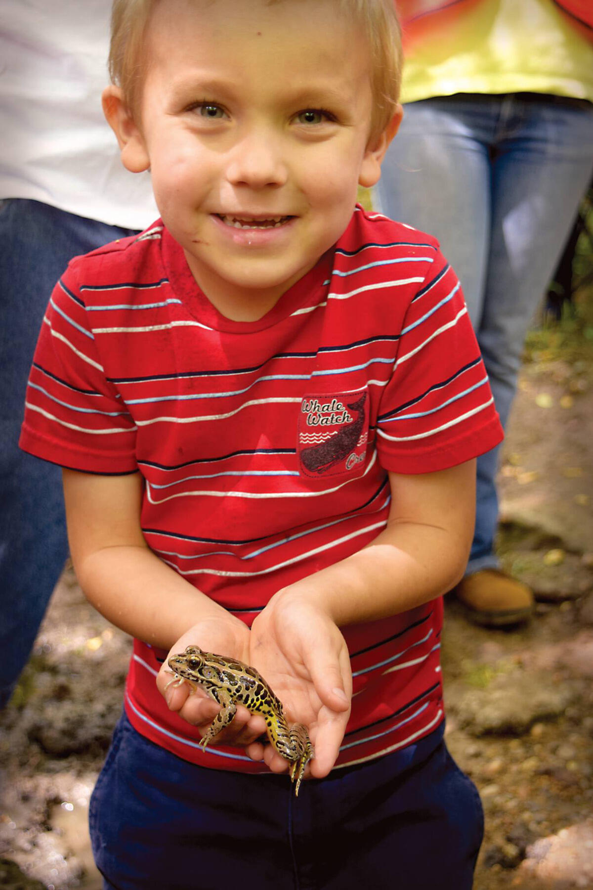 A young volunteer holds a leopard frog.