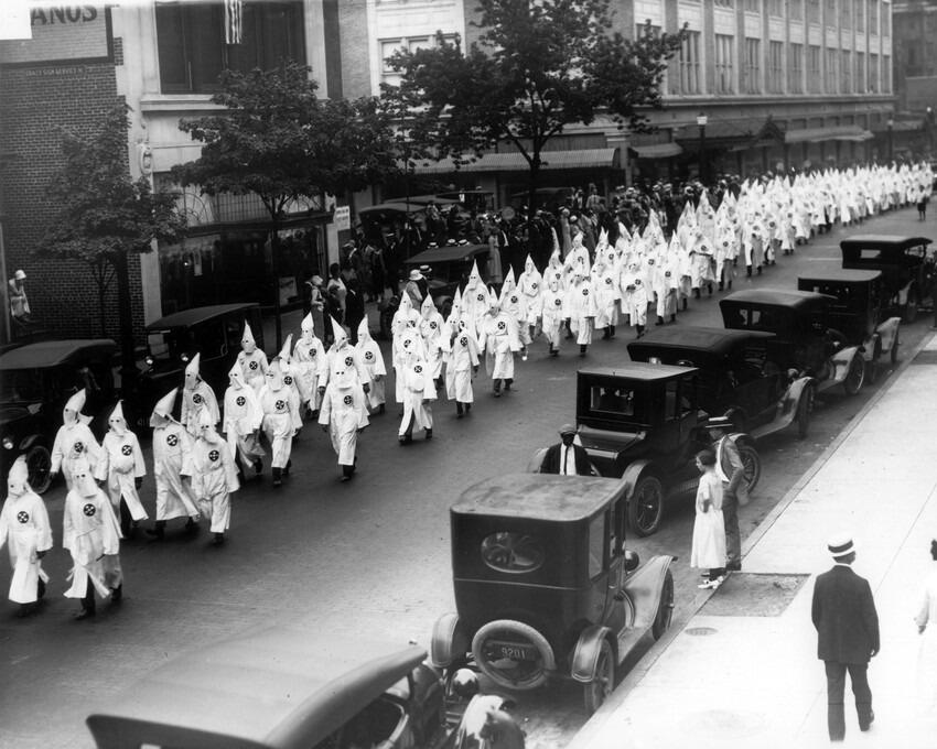 Wearing white robes and hoods, members of the Ku Klux Klan parade on Grace Street in Richmond circa 1925. Image courtesy of The Valentine.