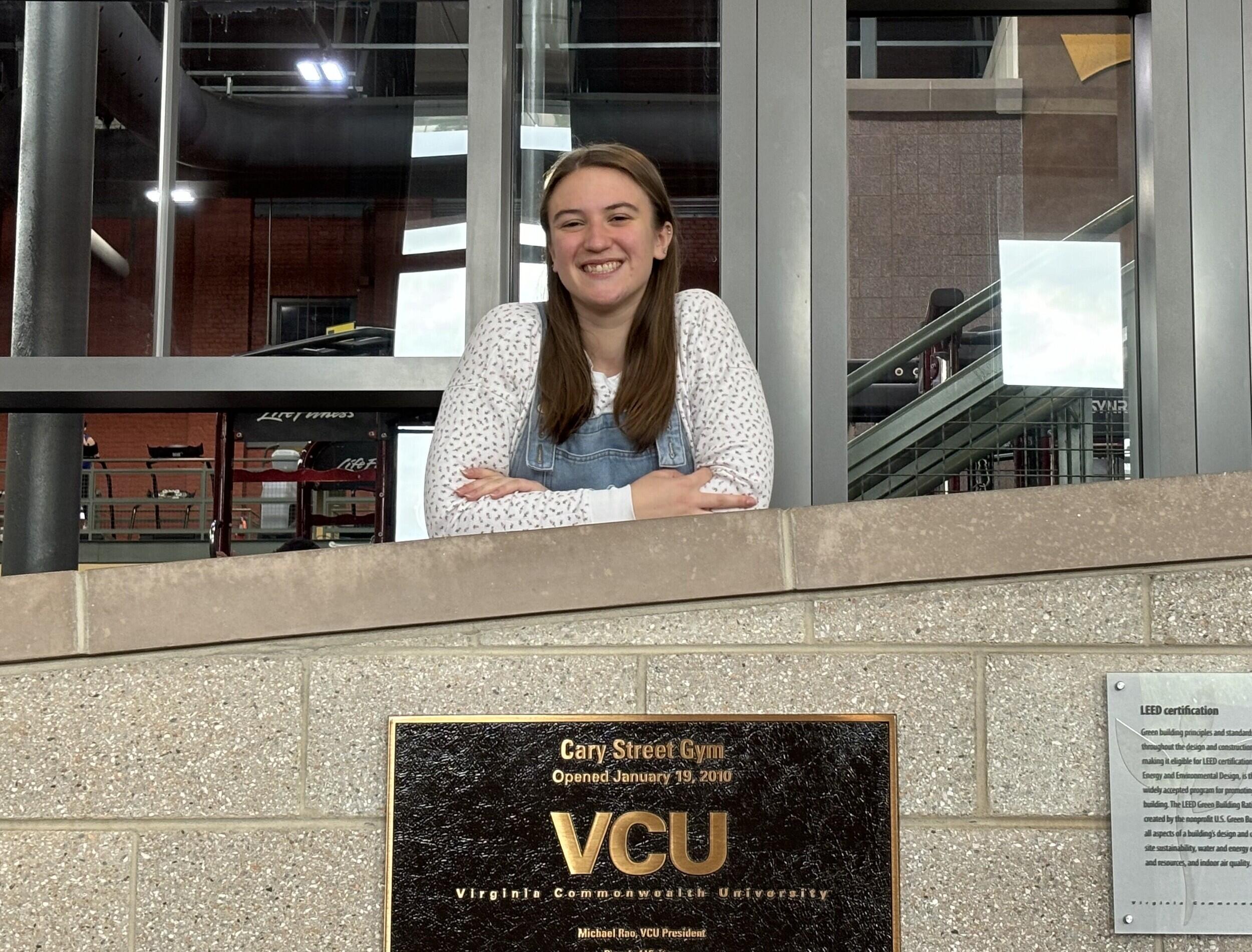 A photo of a woman leaning on a gray brick wall. 