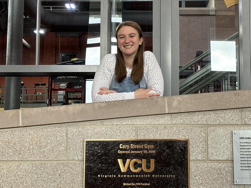 A photo of a woman leaning on a gray brick wall. 