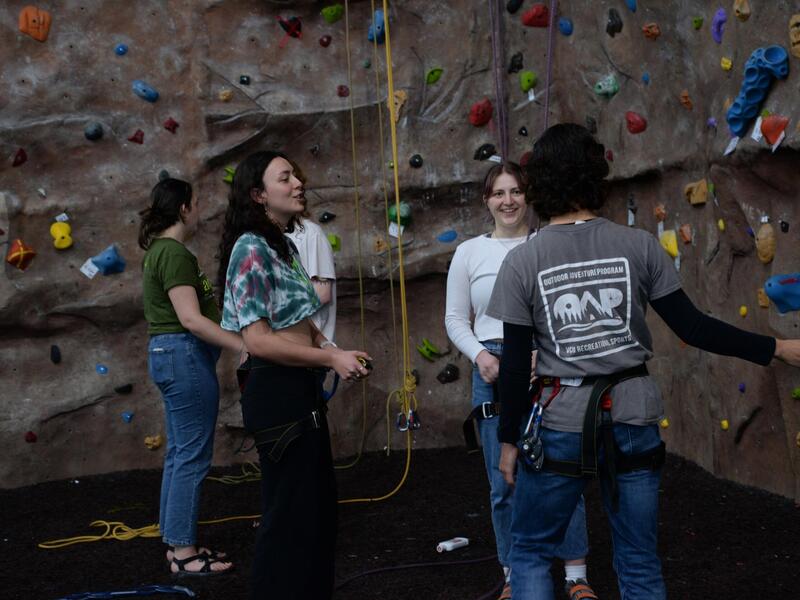 A group of students standing in front of the rock wall at the Cary Street Gym