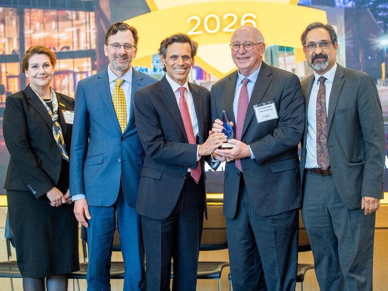 A group photo of four men and one woman standing. 