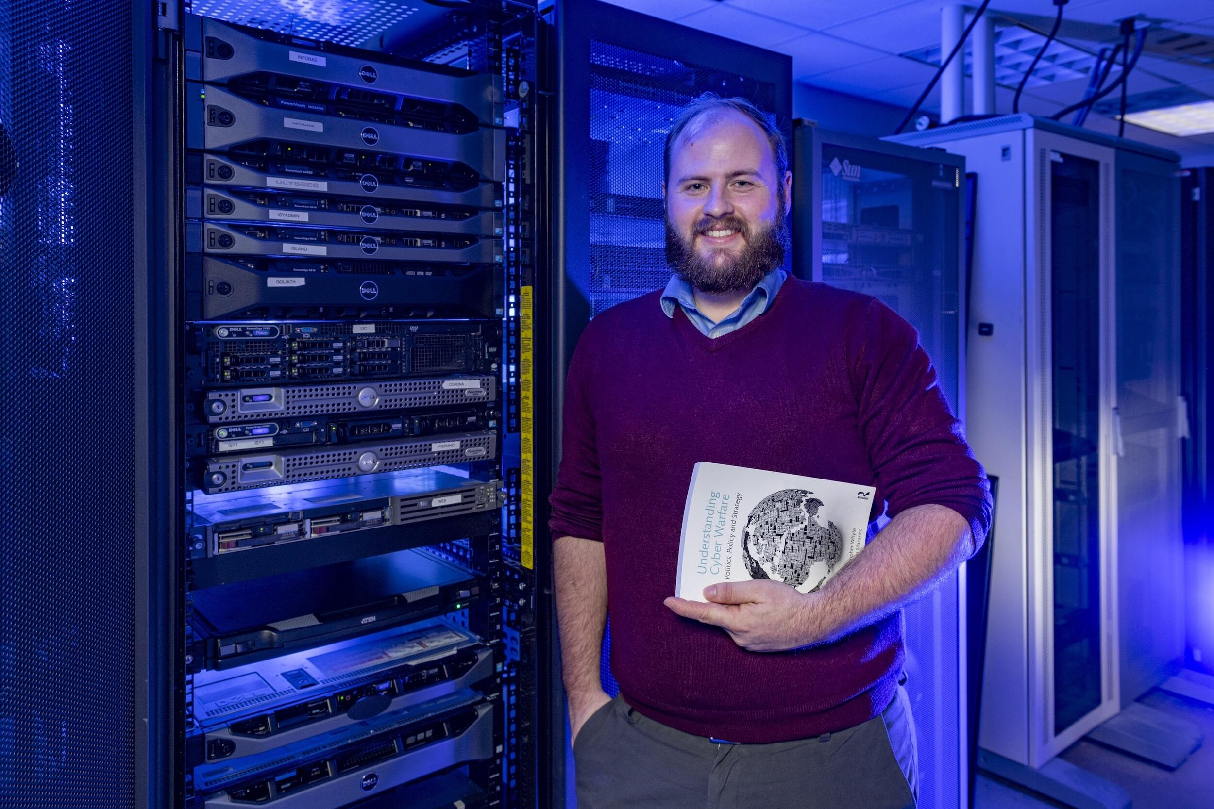 Christopher Whyte, Ph.D. standing next to a server stack.