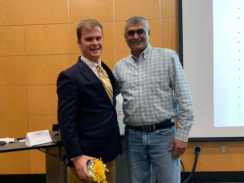 A photo of two men standing next to eachother. The both have one arm placed behind the other man's back. 