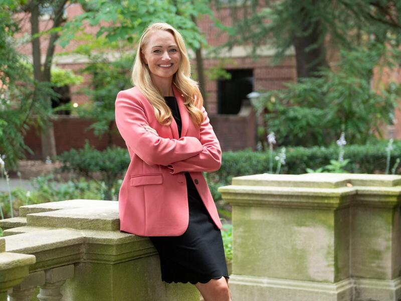 A woman leaning against a stone fence 