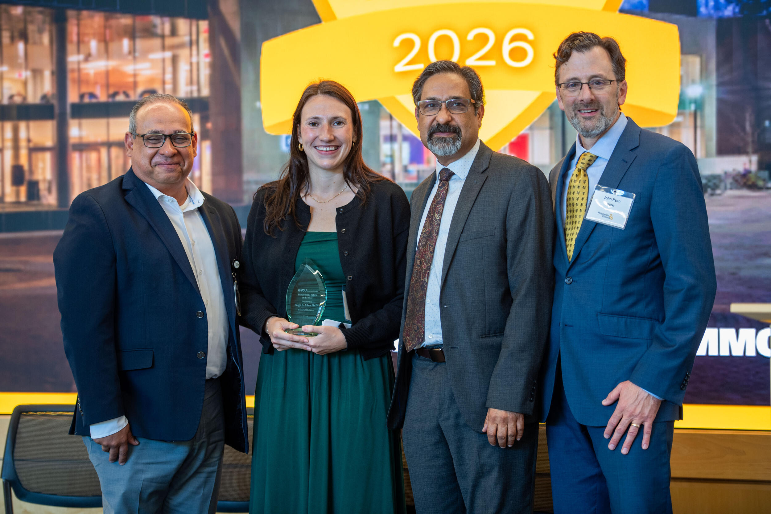 A group photo of three men and one woman. 