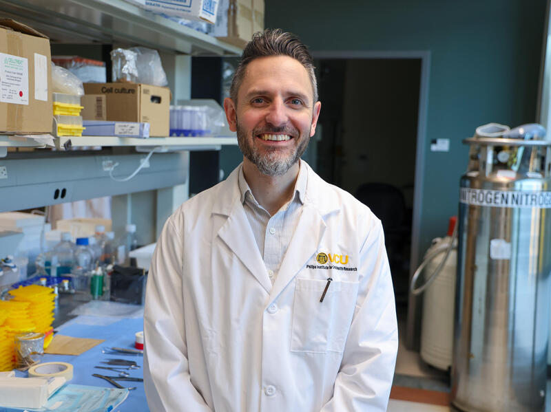 A photo of a man in a lab coat from the waist up. 