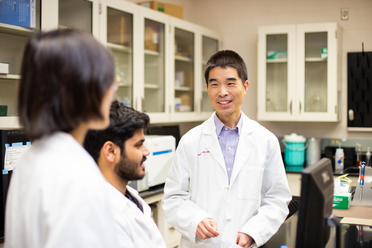Three people in a science lab talking to each other 