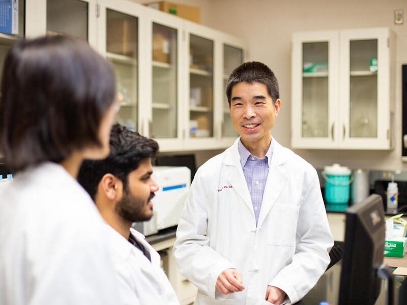 Three people in a science lab talking to each other 
