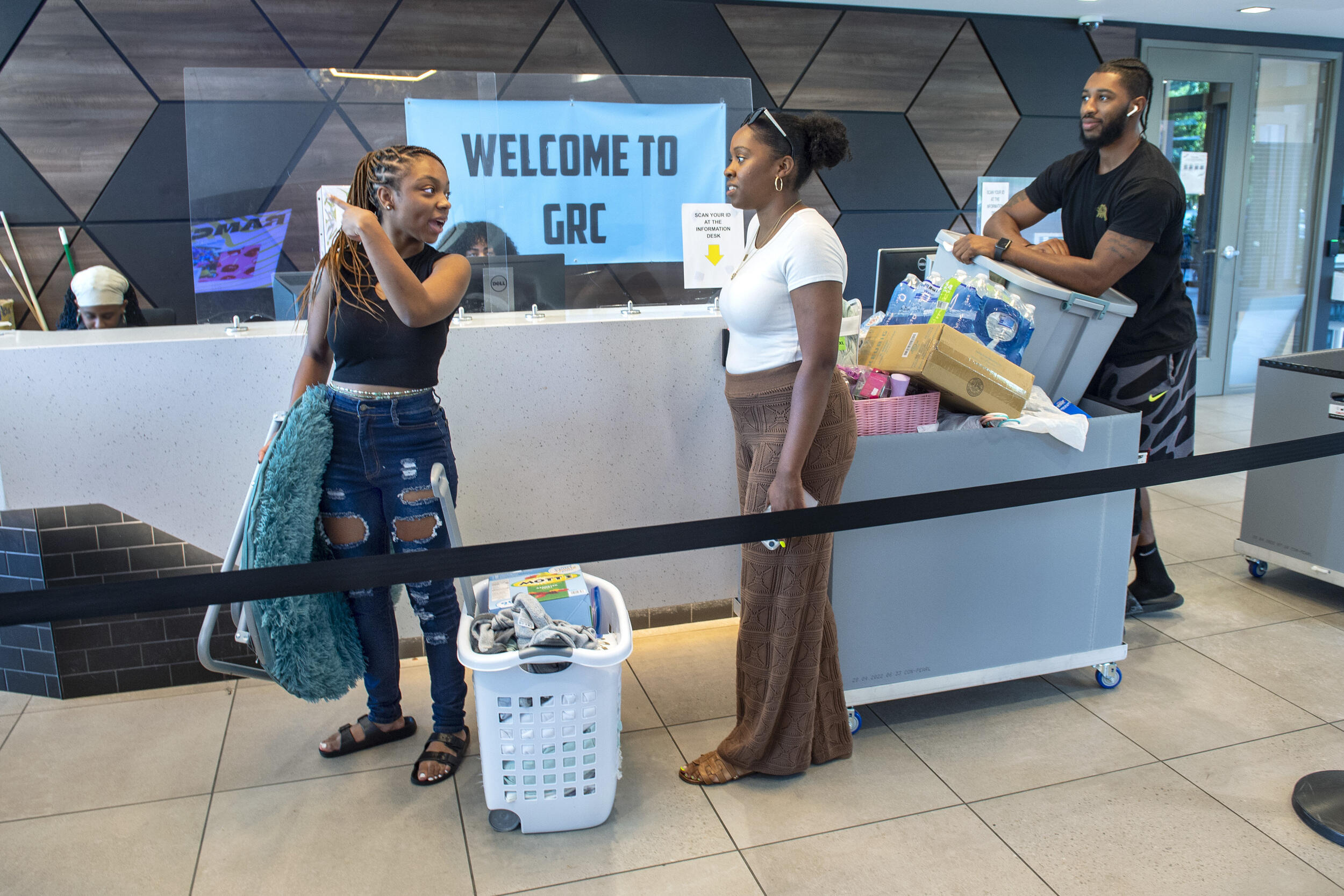 A woman holding a fold up chair pointing to the left while looking at a woman next to her 
