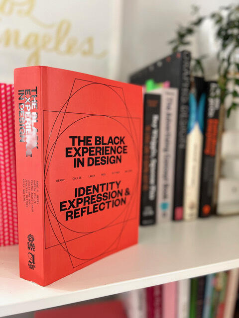 A hardback copy of the book \"The Black Experience in Design: Identity, Reflection & Expression\" sitting on a bookshelf 