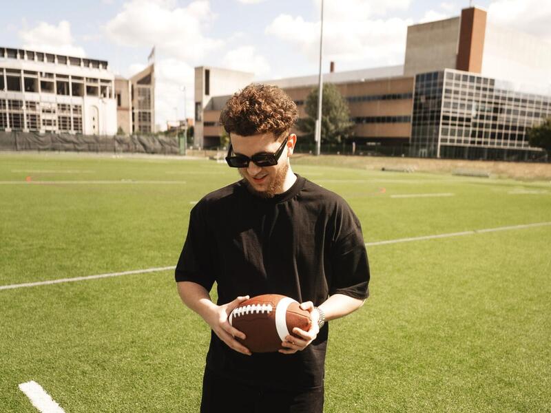 A photo of a man standing on a football field holding a football 