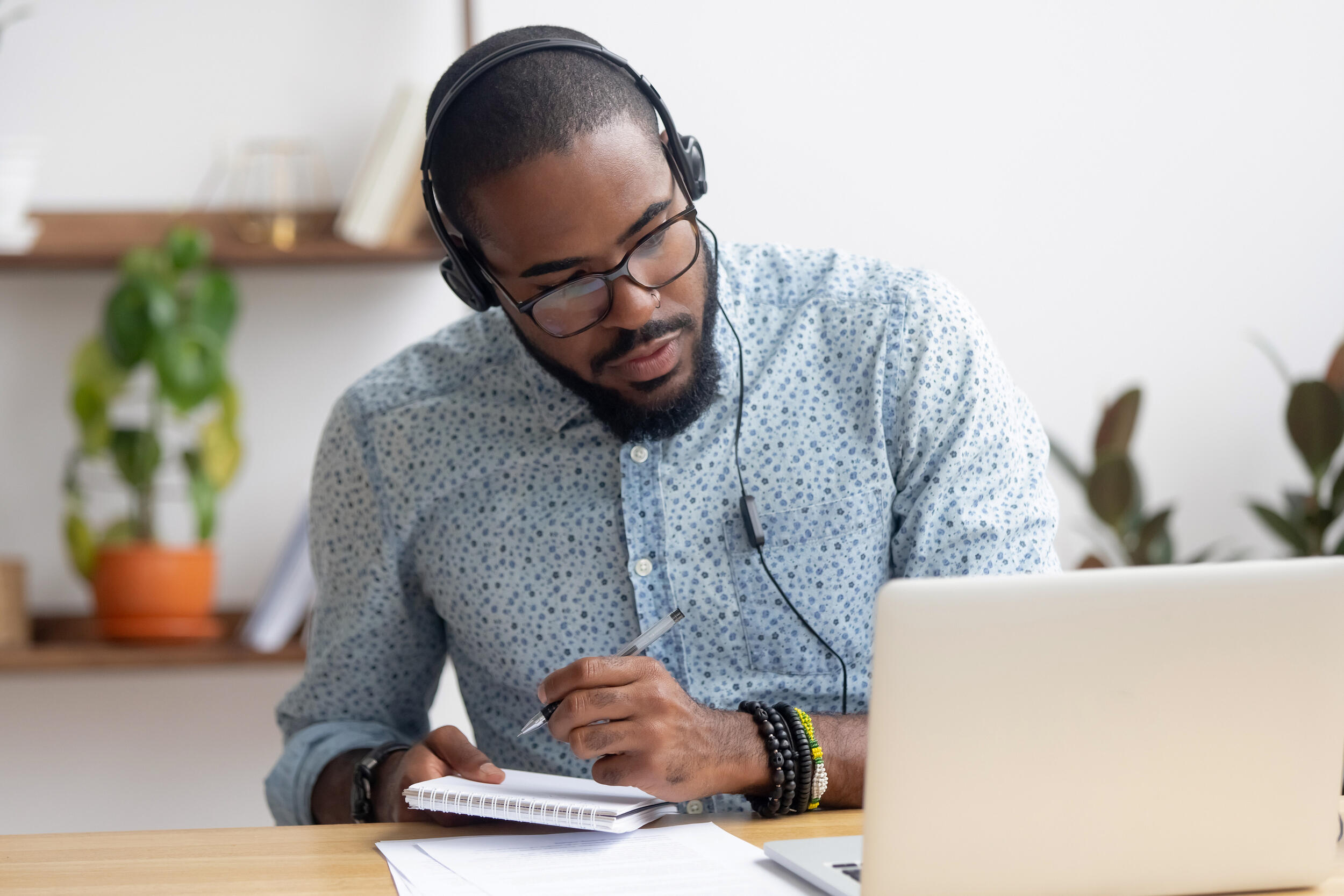 A headphones-wearing person working on a laptop computer.