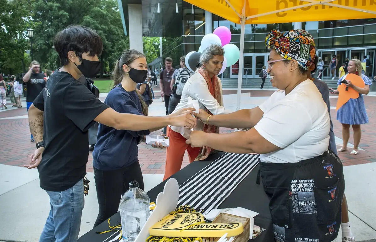A woman handing two people ice cream 