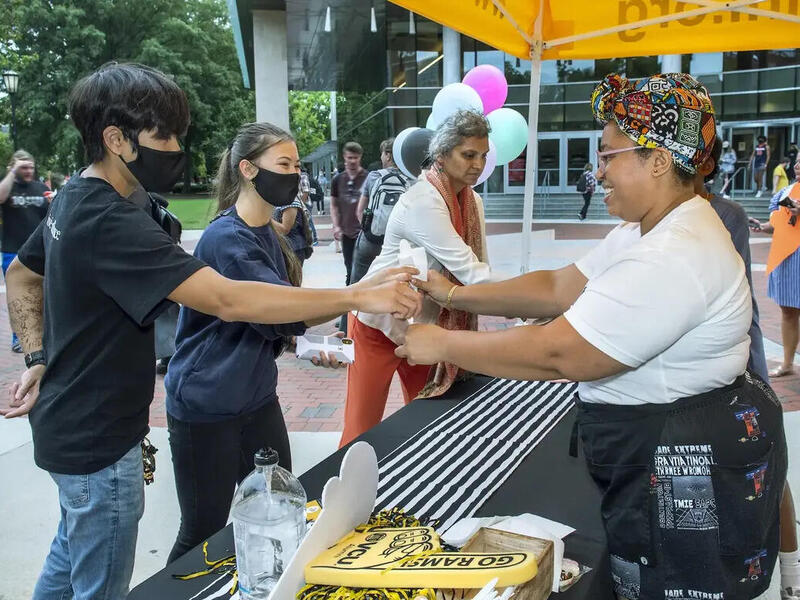 A woman handing two people ice cream 