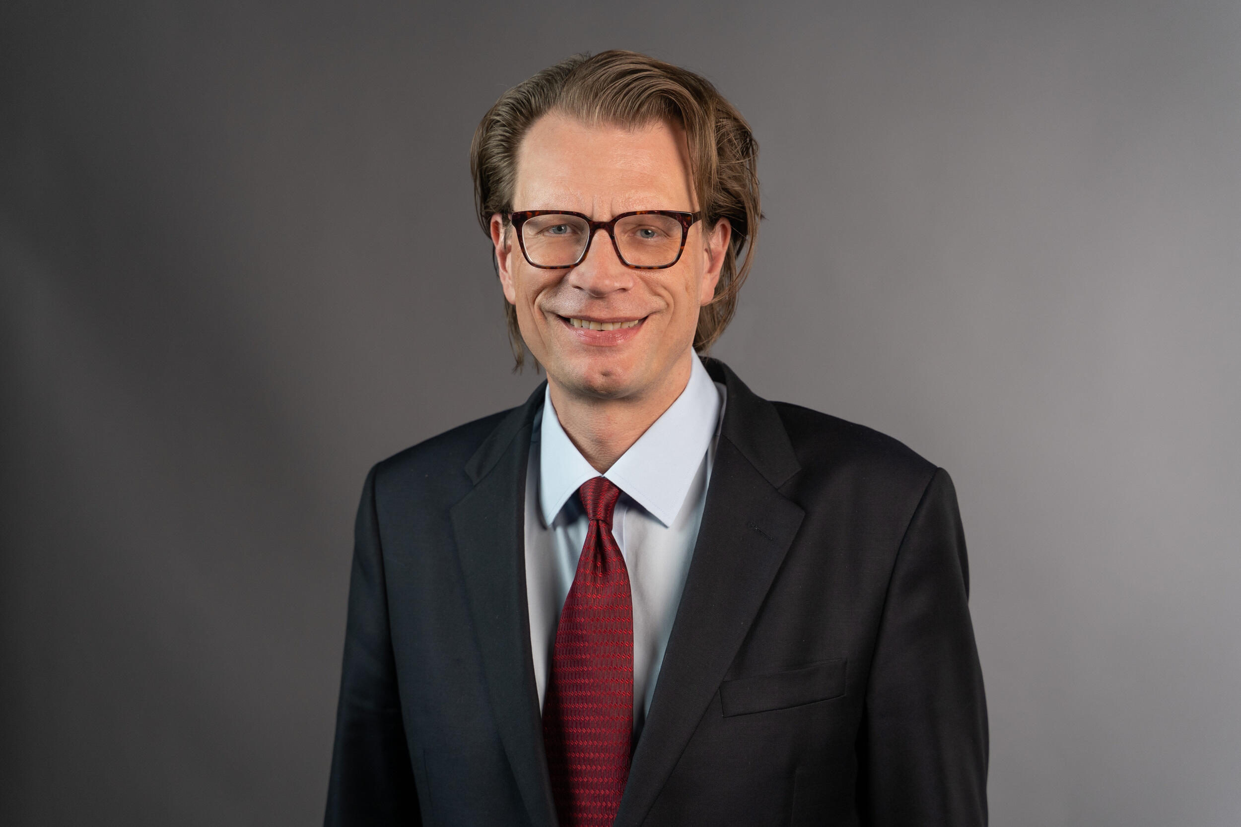 A man in glasses and a coat and tie.