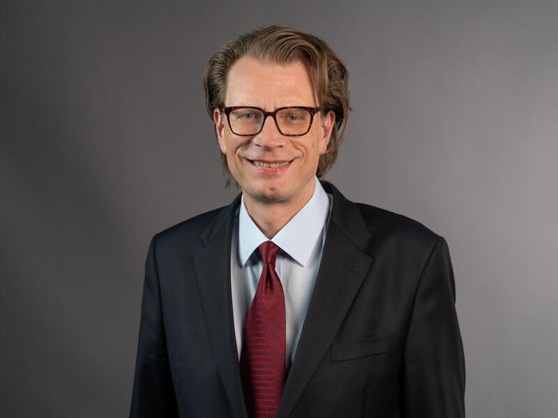 A man in glasses and a coat and tie.