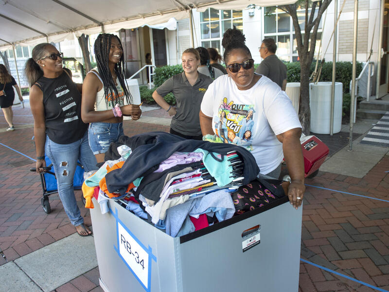 Four women standing around a rolling bin 