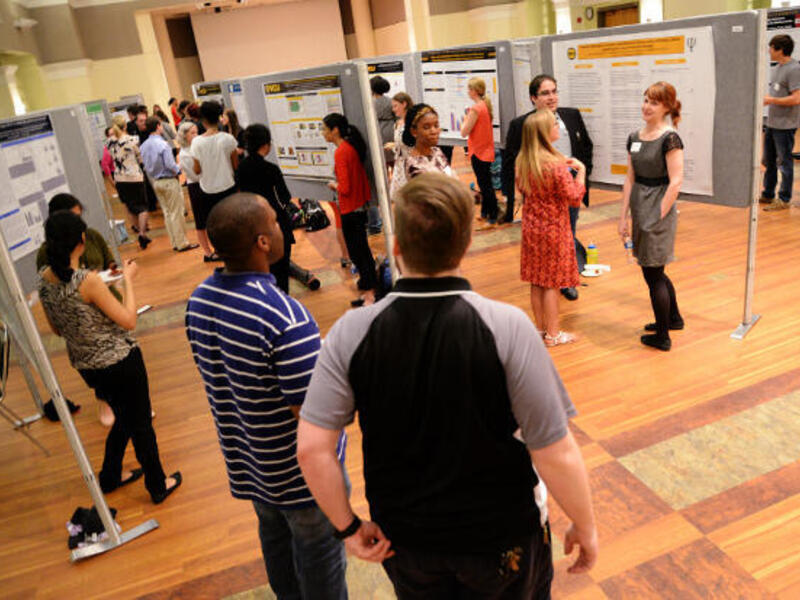 A photo of people walking through a room full of posters. 