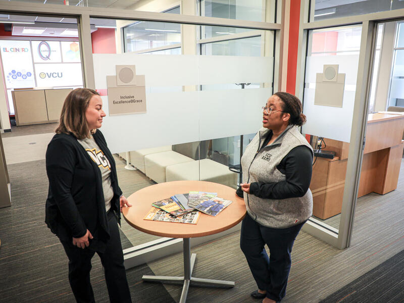 Malorie Yeaman, Title IX coordinator and director of outreach and support at VCU, speaks with Cleopatra Magwaro, associate vice president of institutional equity and interim Americans with Disabilities Act coordinator. They are standing and talking to each other across a small table.