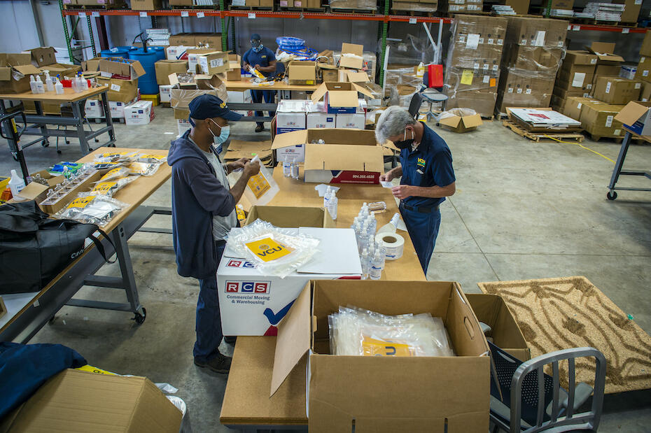 A group of people assembling personal protective equipment supply kits.