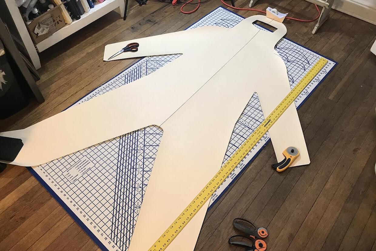 A cardboard cutout of a personal protective suit lying on a drafting table.