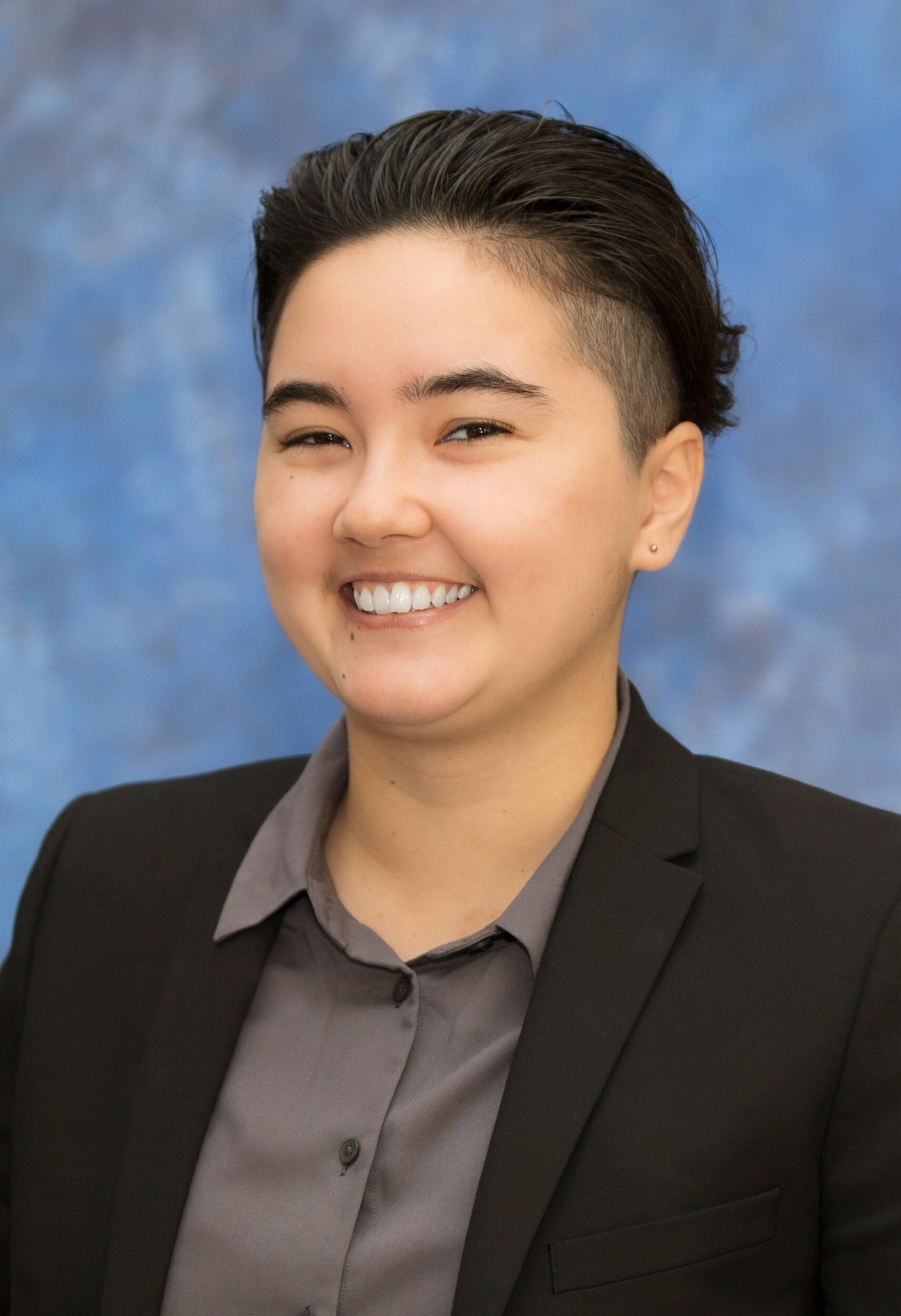 A portrait of a person wearing a button up shirt and suit jacker 