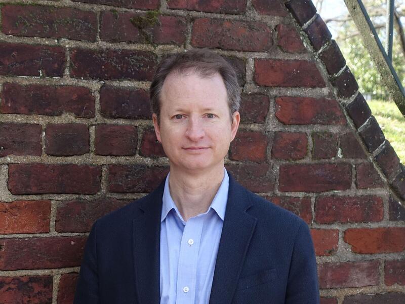 Portrait of Ryan Smith in front of a brick wall.