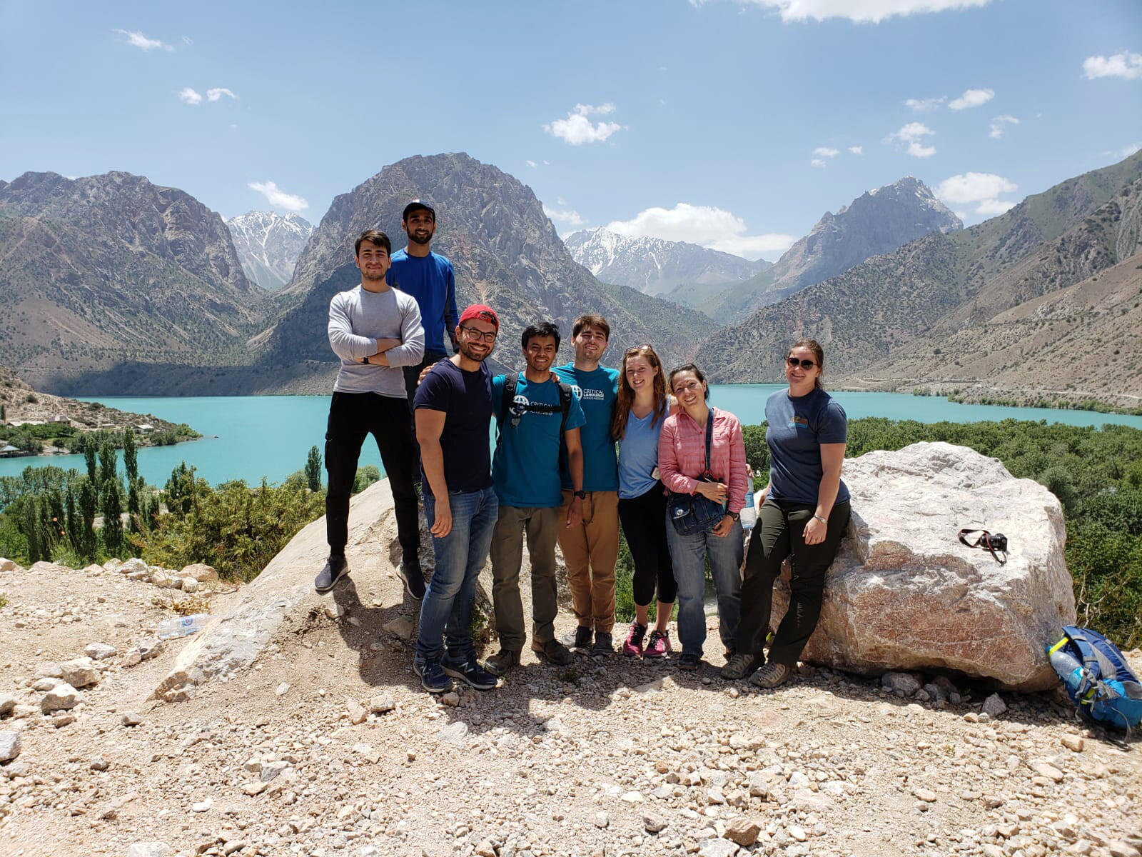 A group of people stands at a scenic lake overlook.