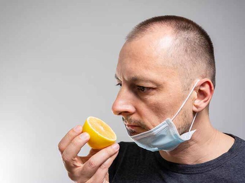 Man wearing a mask smells a lemon
