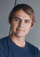 A headshot of a man wearing a dark blue shirt 
