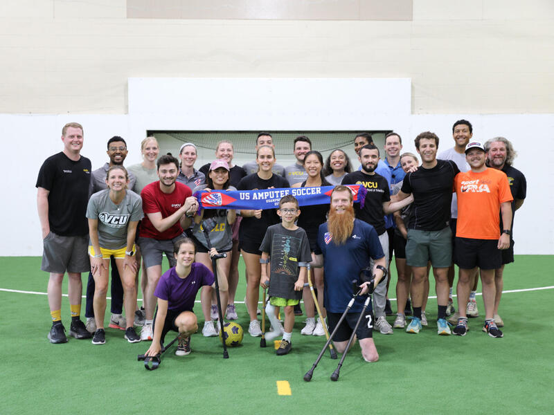 A group photo of 22 adults and one child. 