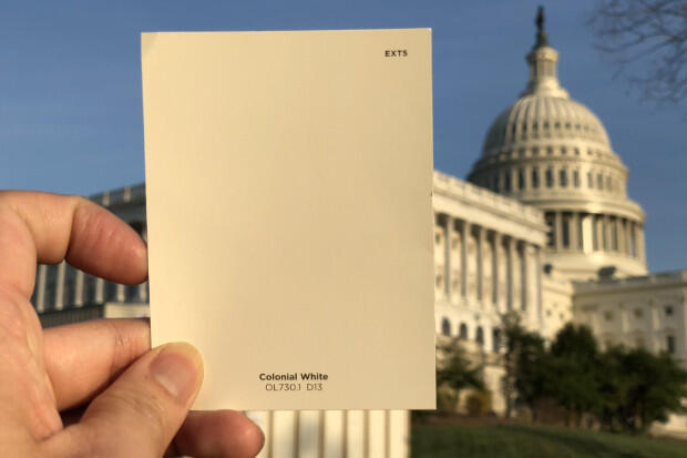 Paint chip held up in front of large building.