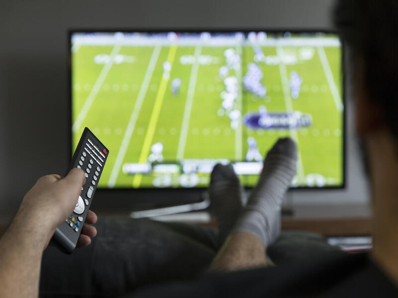 A person sitting and watching a sports event on television.