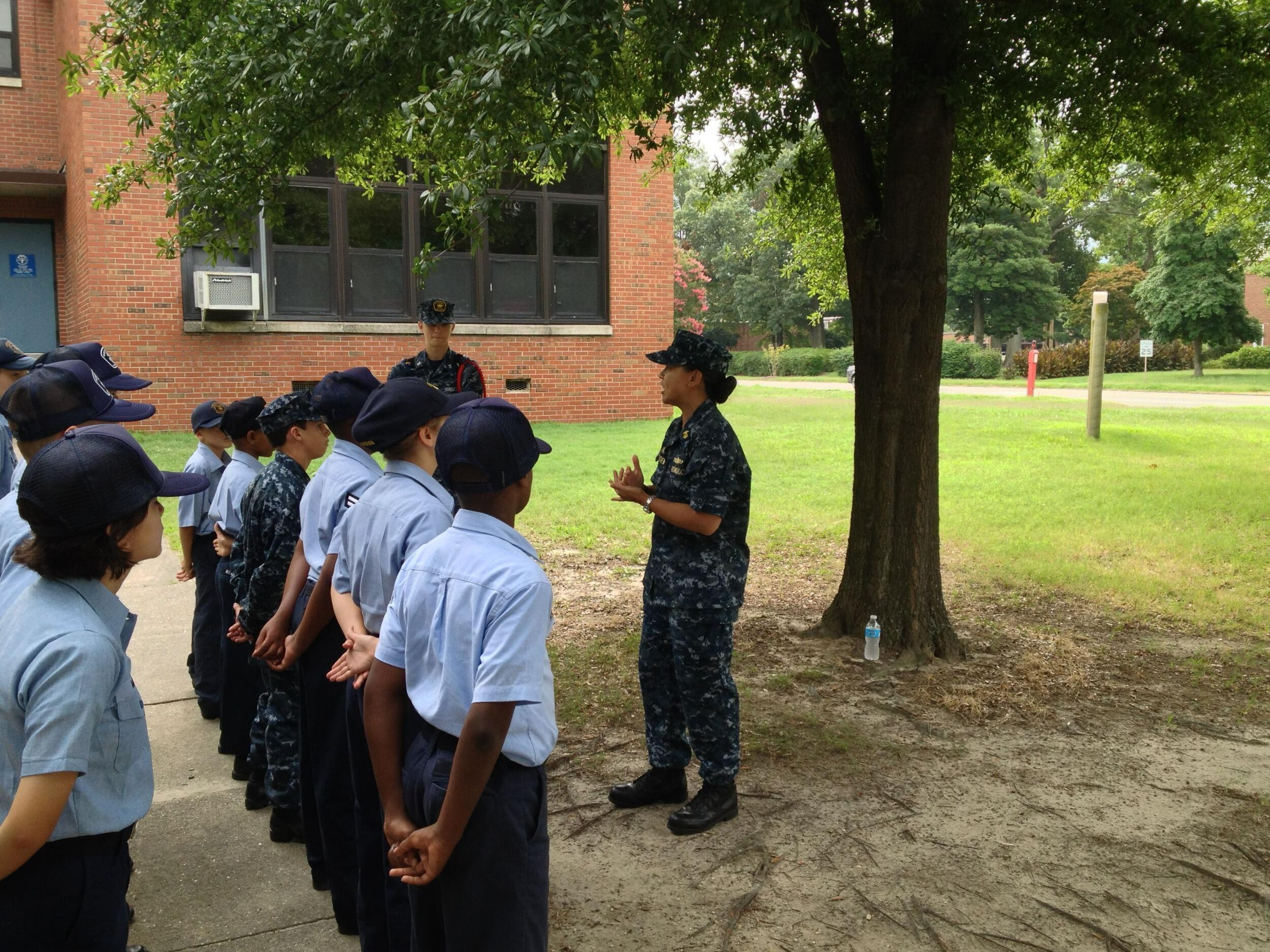 A photo ofa woman in a military uniform talking to a group of people
