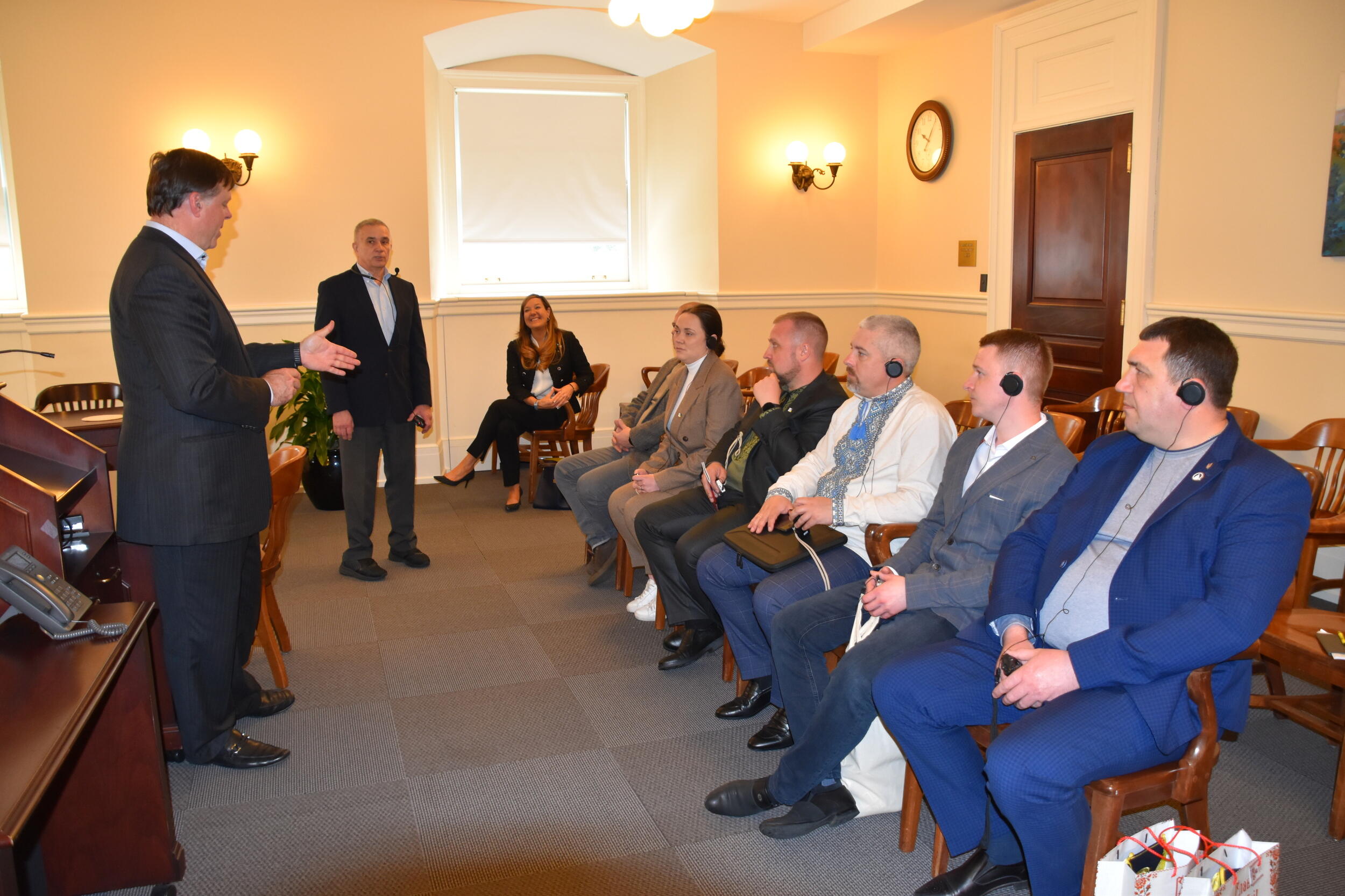 People sitting in chairs in a room watching a man talk