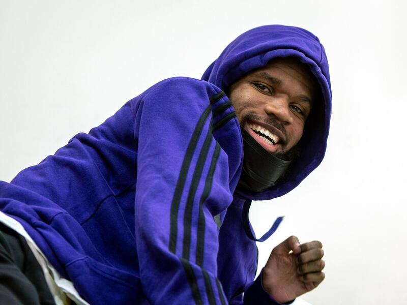 A photo of a man smiling and leaning to the side while looking down. 