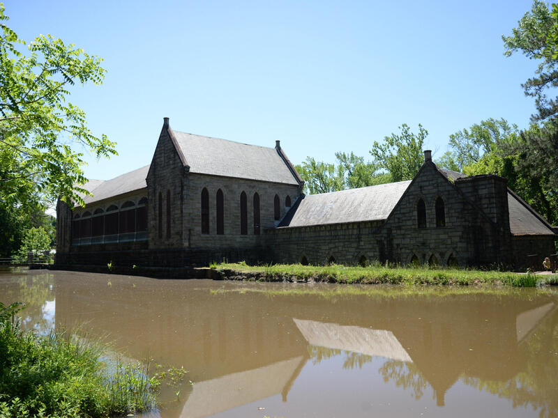 A small body of water is in the foreground before a pump house building.