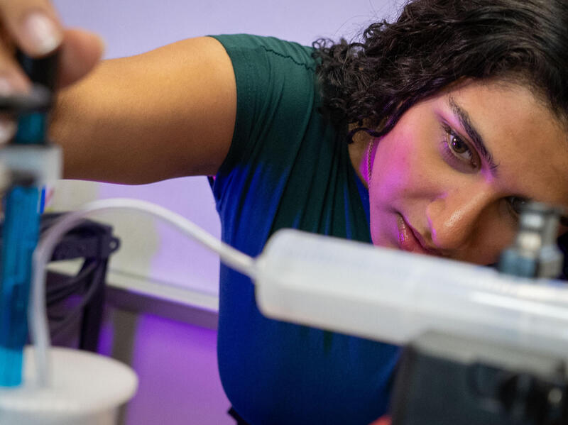 A photo of a woman looking closely at scientific equipment. 