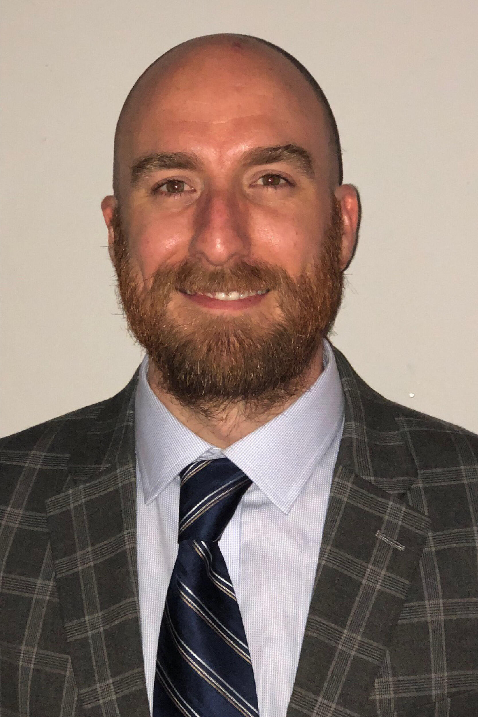 A photo of a man wearing a suit and tie from the chest up. 