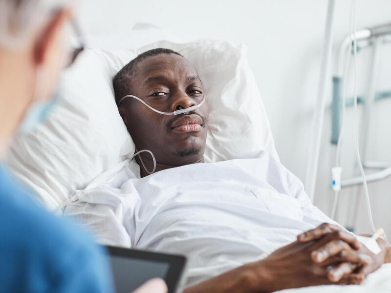 A man sitting in a hospital bed looking at a healthcare provider 