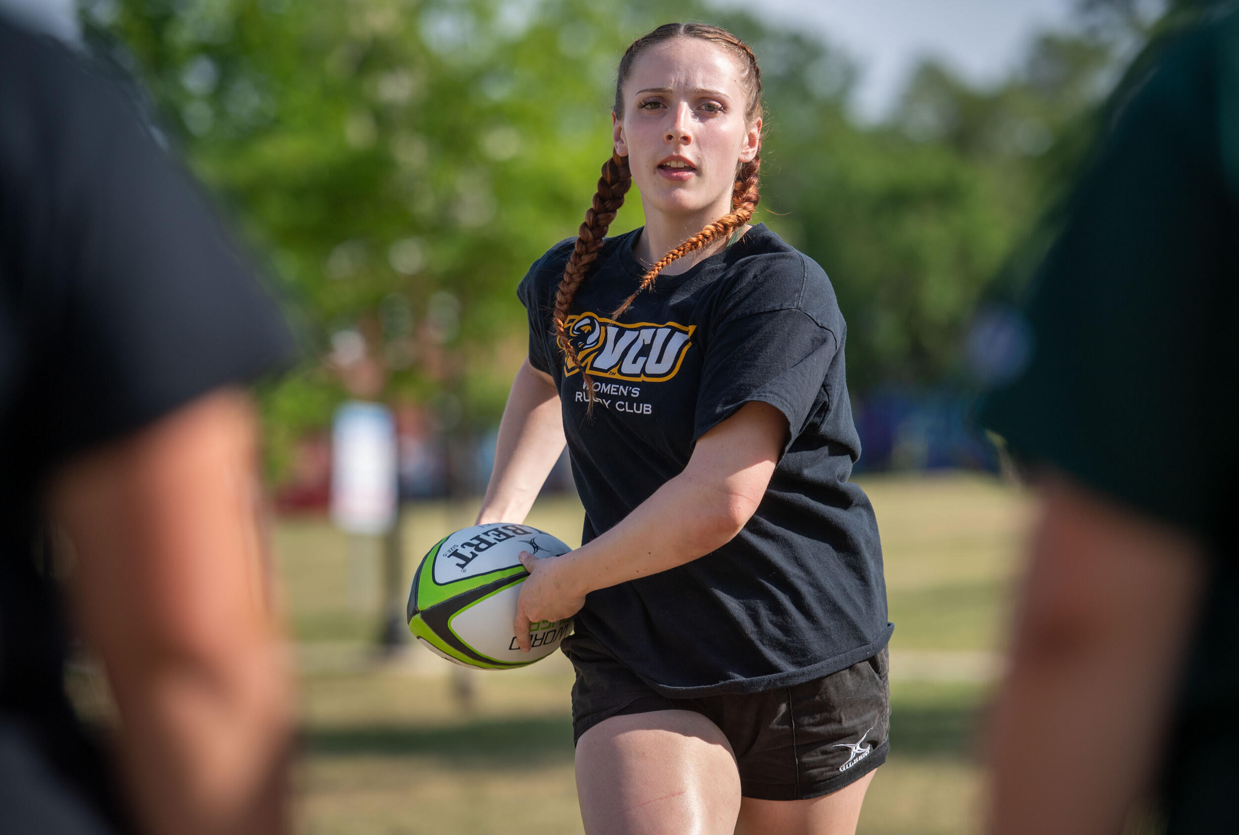 A photo of a woman holding a ball and running on a field.