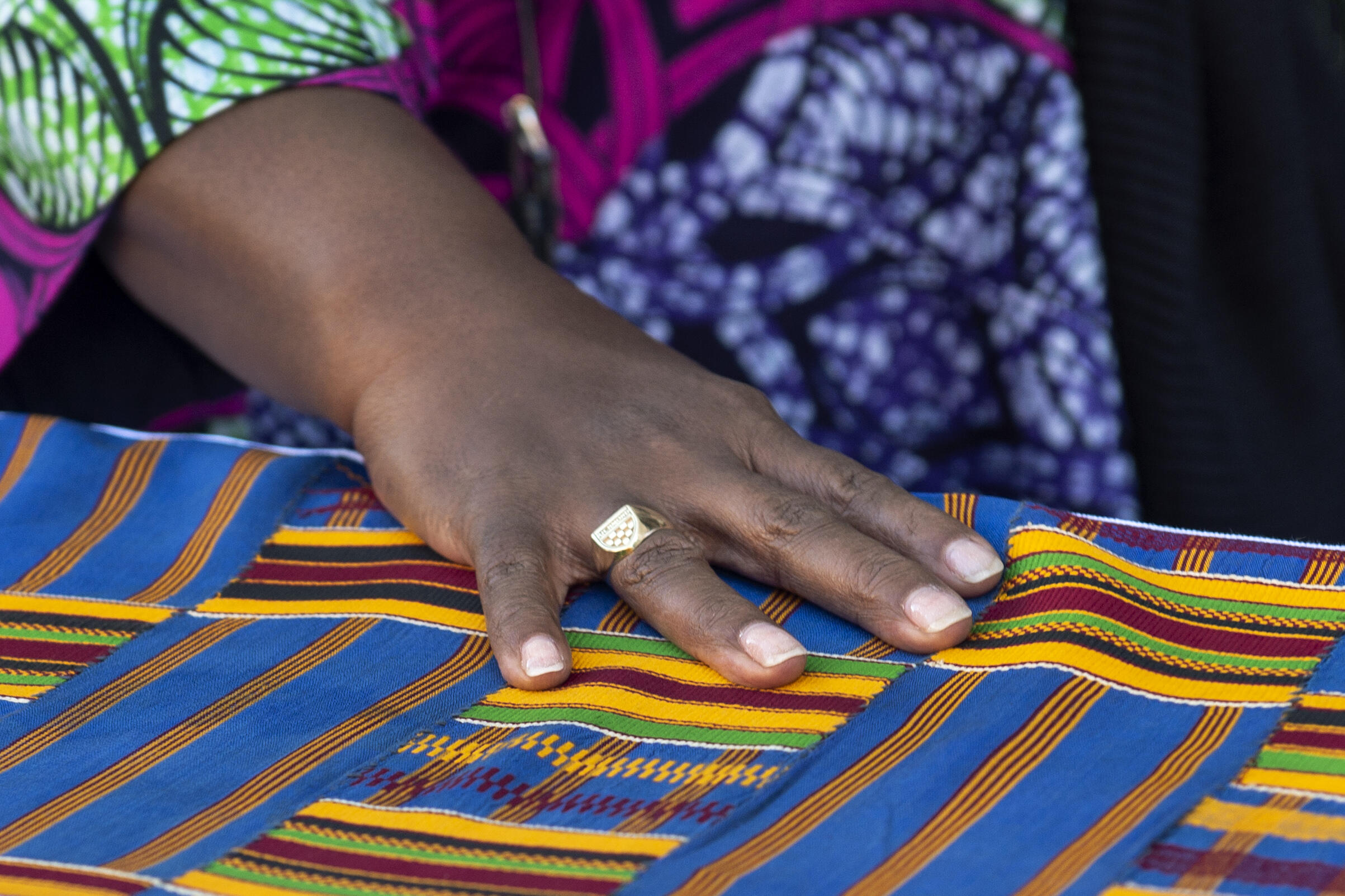 A photo of a hand on a piece of multicolored fabric. 