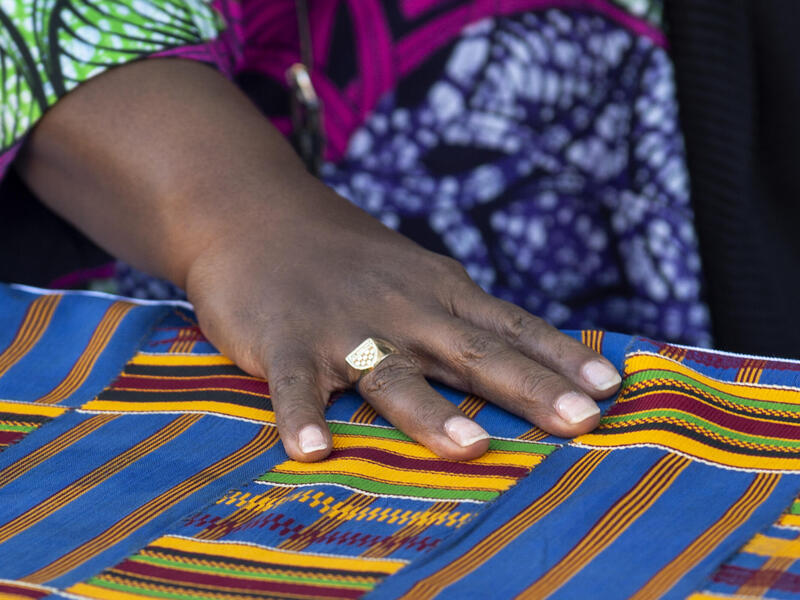 A photo of a hand on a piece of multicolored fabric. 