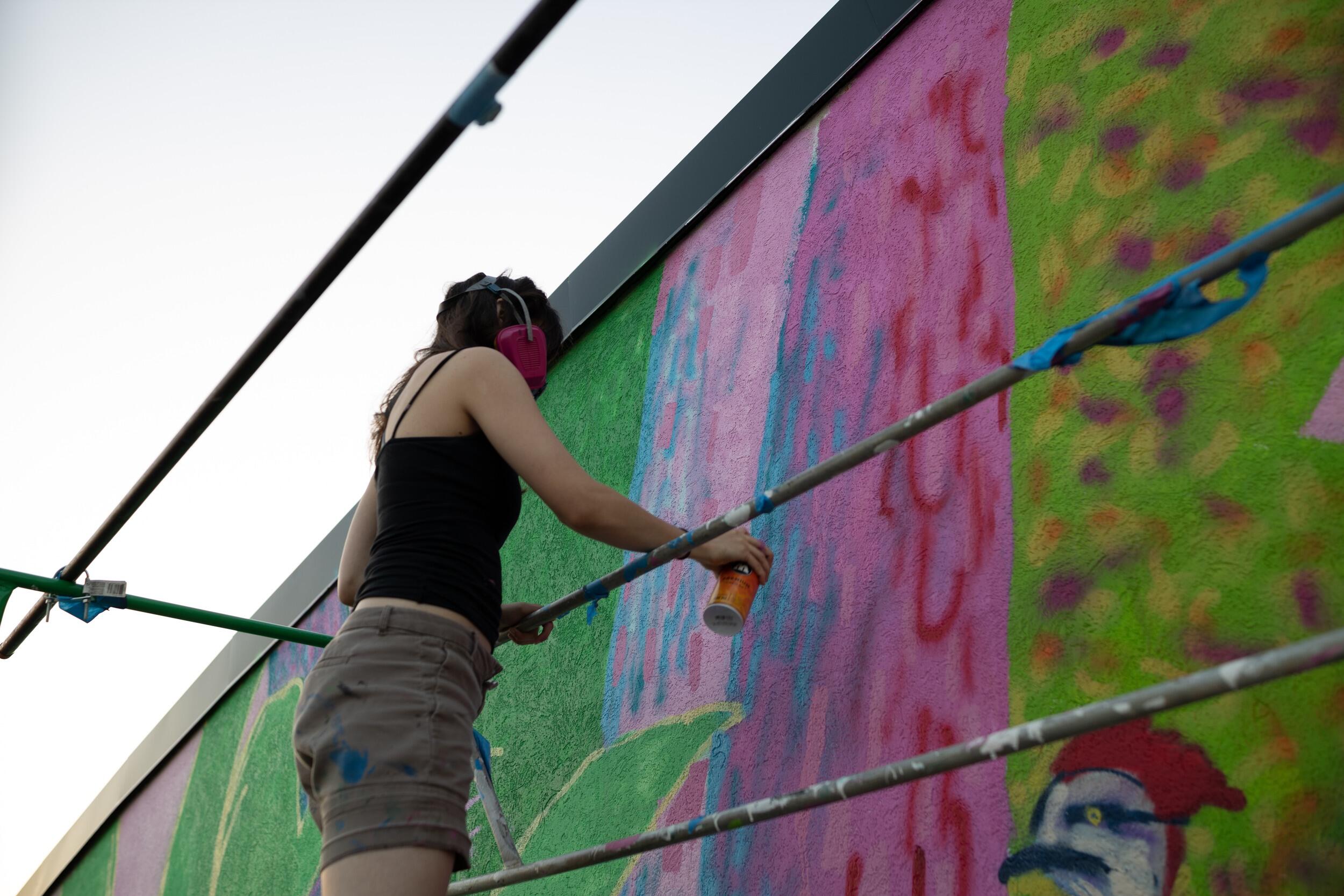 A woman painting the side of a building