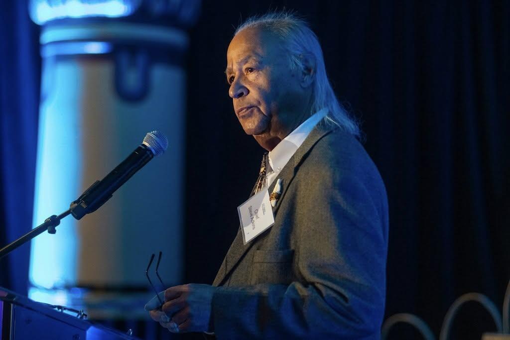A photo of a man standing behind a podium. 