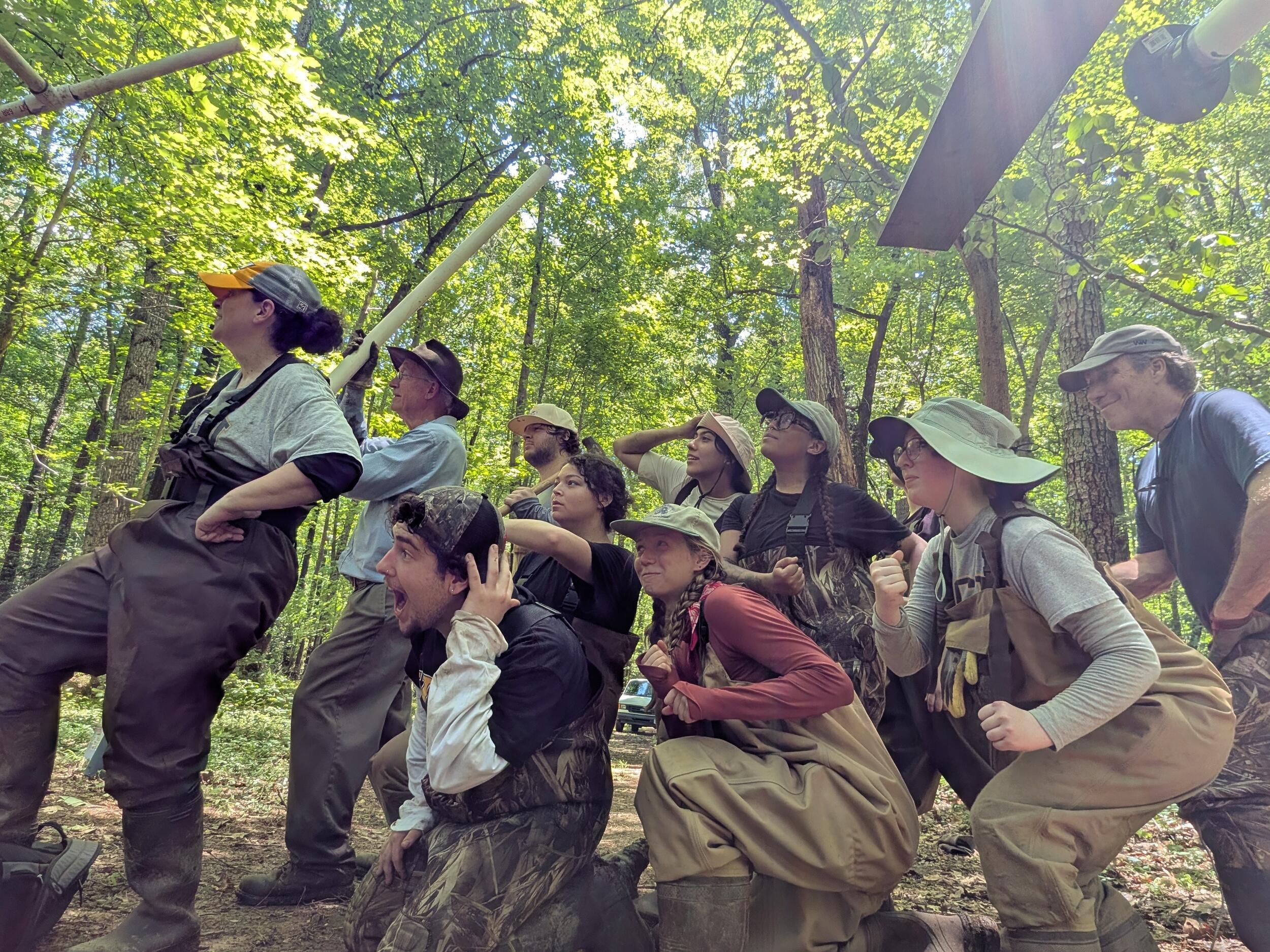 A group photo of 10 people in the woods looking ot the left. 
